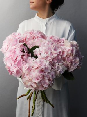 Ragazza camicia bianca tiene in mano un Bouquet di Ortensie di colore rosa