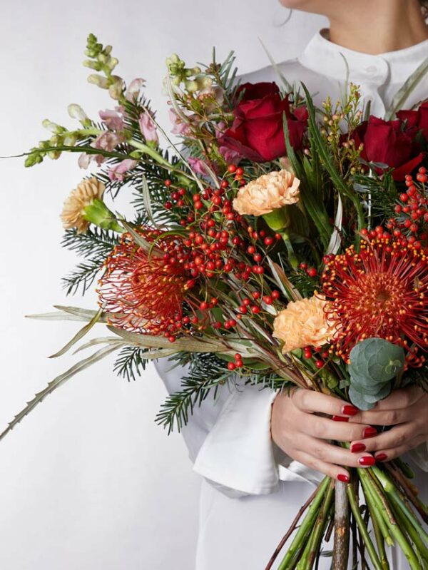 Bouquet Incanto d'Inverno rose rosse, bocche di leone rosa, bacche rosse, nutan, garofani salmone e verde di stagione