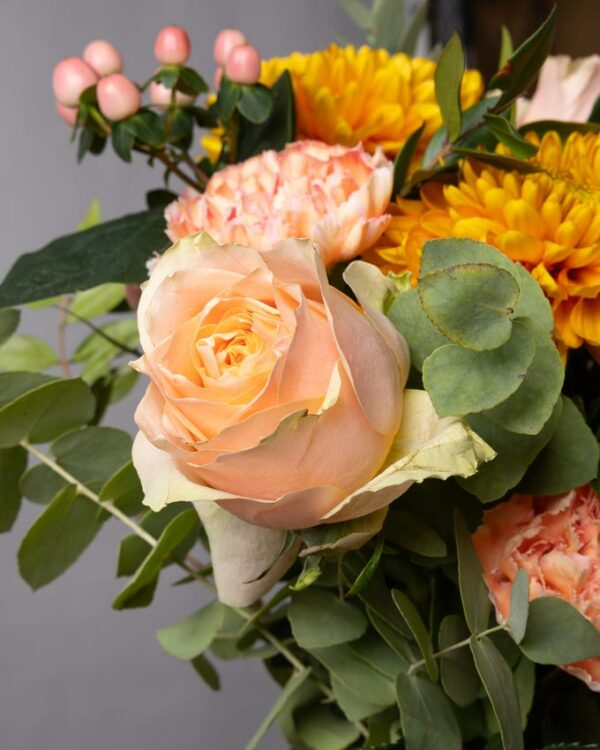 Rose rosa, crisantemi arancioni, garofani arancio, iperico rosa e verde di stagione nel bouquet di fiori Bouquet Tangerine