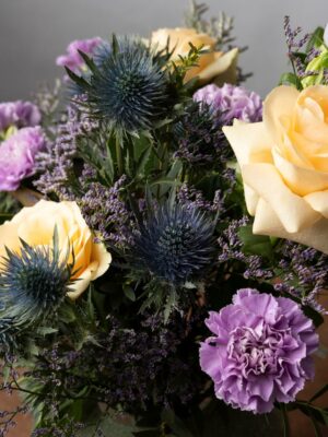 Bouquet Sweet Dreams dettaglio di rose pesca, garofani lilla, eryngium, limonium viola e campanule lilla. I colori della Primavera