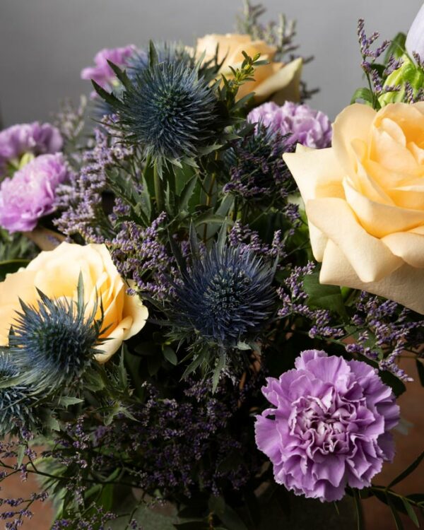 Bouquet Sweet Dreams dettaglio di rose pesca, garofani lilla, eryngium, limonium viola e campanule lilla. I colori della Primavera